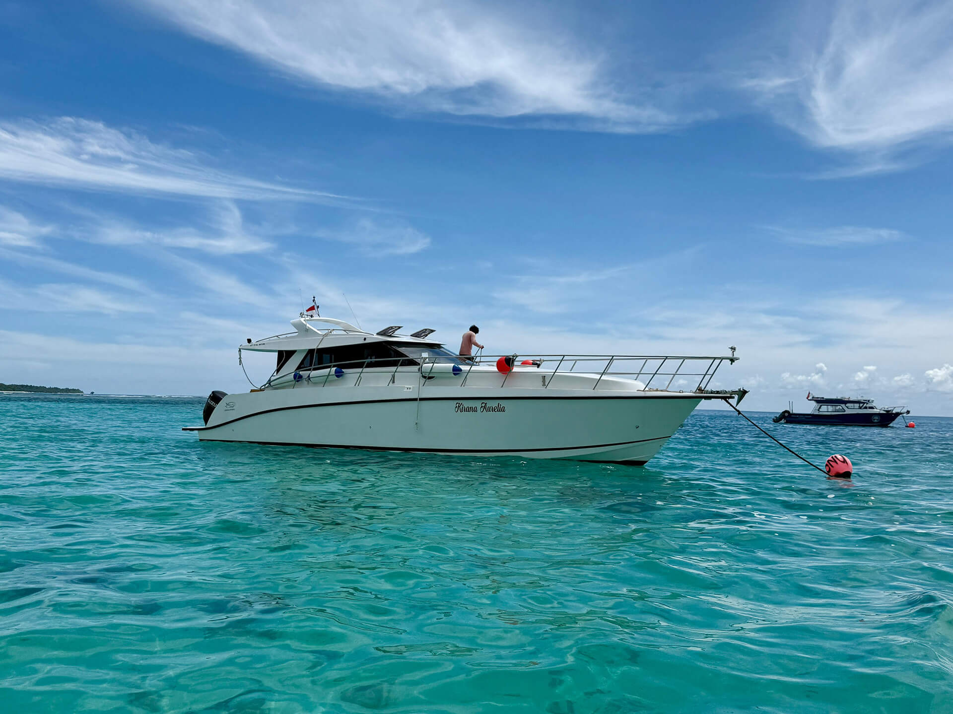 White speed boat from Villa Onu moored to an orange bouy in the tropical blue waters of Mentawai.